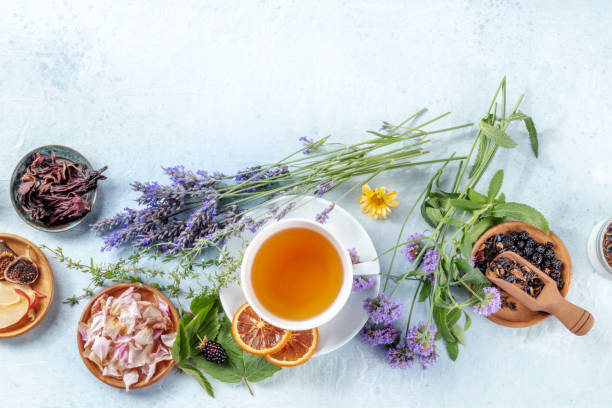 A cup of tea with dry fruit, flowers, and herbs, shot from the top.