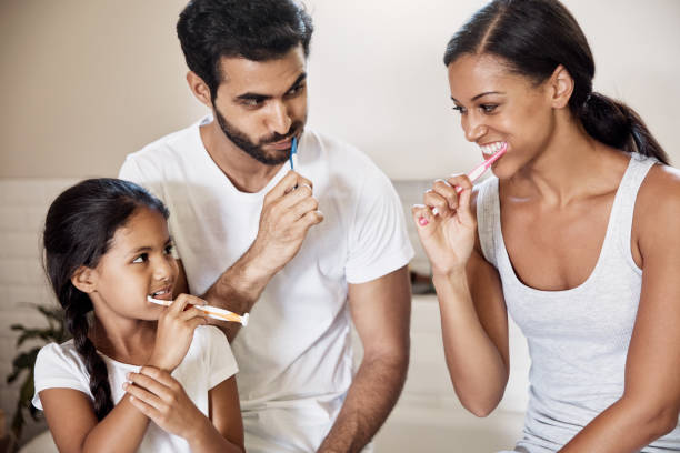 Shot of a family brushing their teeth together in the bathroom