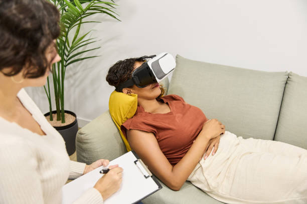 Professional psychologist with clipboard consulting young female client in glasses of virtual reality in office. Concept of mental health.