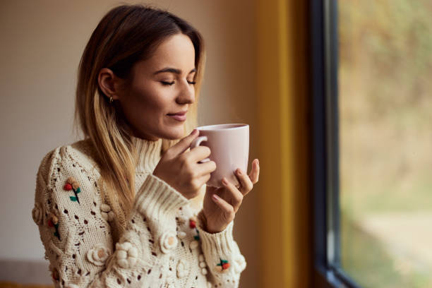 A smiling girl, enjoying her RED coffee, being at home.
